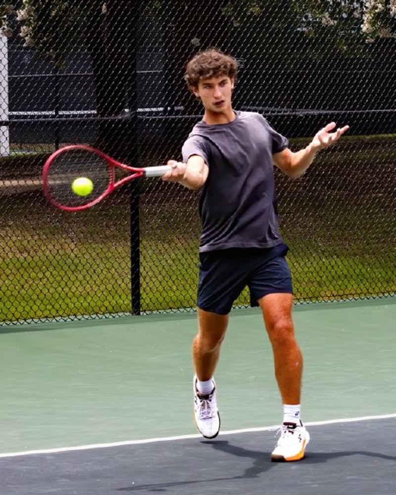 Aidan Peskin hitting a forehand with the ball on the strings